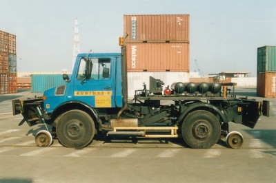 2-Wege-Unimog U1450 im Firmengelände vor klassischer Hafenkulisse