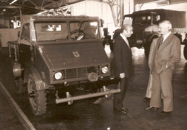 Rennfahr-Legende Juan Manuel Fangio im Gespräch mit Unimog-Versuchsleiter Christian Dietrich in der Unimog-Ablieferhalle Gaggenau. - El campeon mundial Juan Manuel Fangio en discurso con el jefe de ensayos UNIMOG, Christian Dietrich, en la planta UNIMOG de Gaggenau.